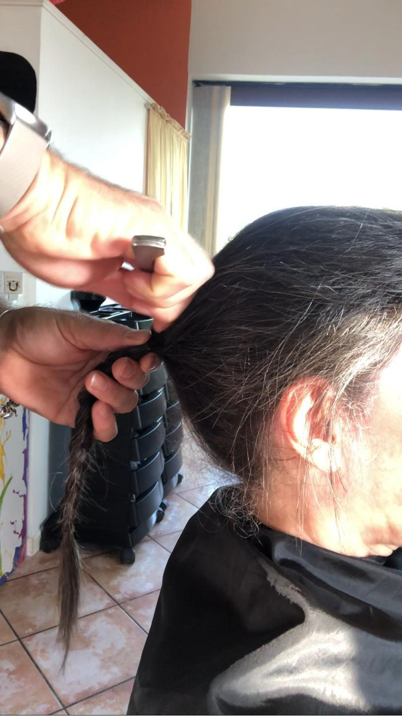 Foto del taglio di una treccia di capelli di donna, ritratta di spalle